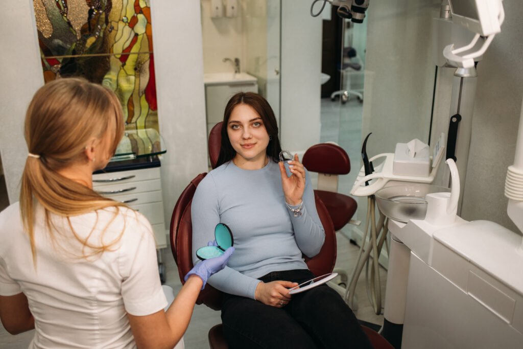 woman holds aligners in dentistry while sitting in dental chair
