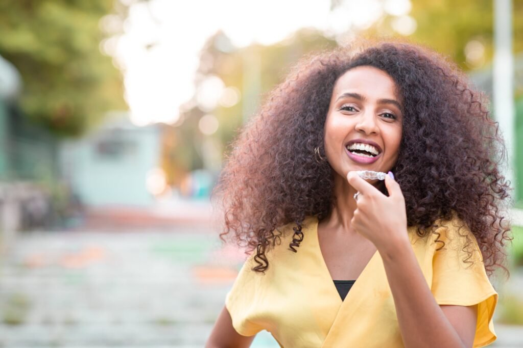 Beautiful smiling African black woman is holding invisaligner. Includes copy and text space.