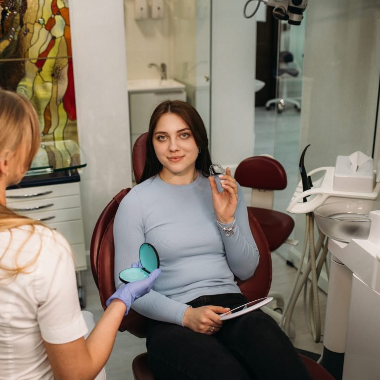 woman holds aligners in dentistry while sitting in dental chair